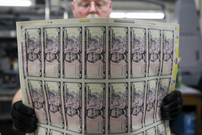 An employee uses a vibrating table to loosen stacks of $5 notes before they are cut into singles at the Bureau of Engraving and Printing in Washington.    Bloomberg