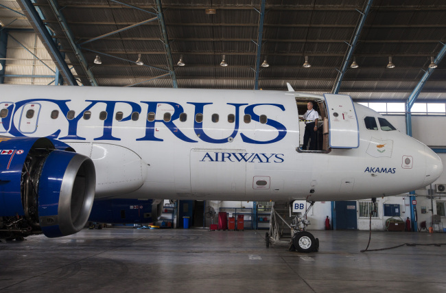 A Cyprus Airways engineer looks out from the doorway of an Airbus A320 aircraft during routine servicing in a hangar at Larnaca international airport in Larnaca, Cyprus.   Bloomberg