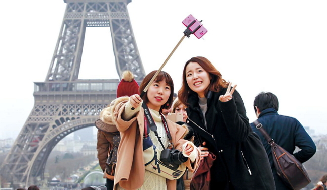 Tourists use a selfie stick at Trocadero Square, with the Eiffel Tower in background, in Paris. (AP-Yonhap)