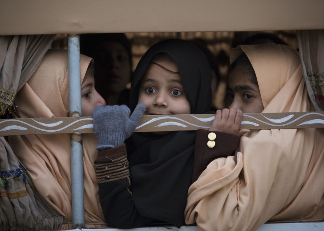 Pakistani students look out from a vehicle on their way to school near the Army Public School, which was targeted by Taliban militants last year, in Peshawar, Pakistan, Monday. Children and staff returned to the school in northwestern Pakistan where about a month ago Taliban gunmen killed 150 people, almost all of them students.   AP-Yonhap