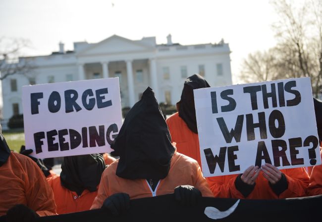 Hooded protesters, some holding placards, take part in a demonstration against the Guantanamo Bay detention facility outside the White House in Washington, Sunday.   AFP-Yonhap
