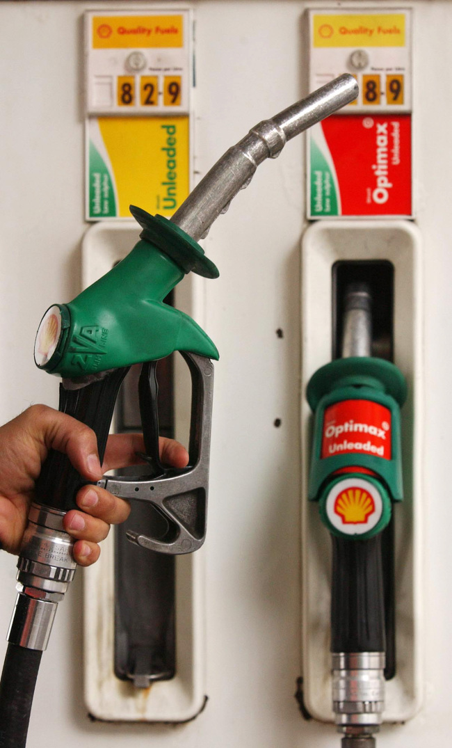 A customer holds a nozzle at a petrol station in London.   Bloomberg