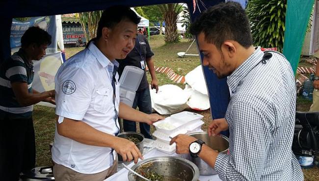 Businessman Ferry Alfiand serves food, which he brought from his restaurant, to the search personnel at the operations center.    Straits Times