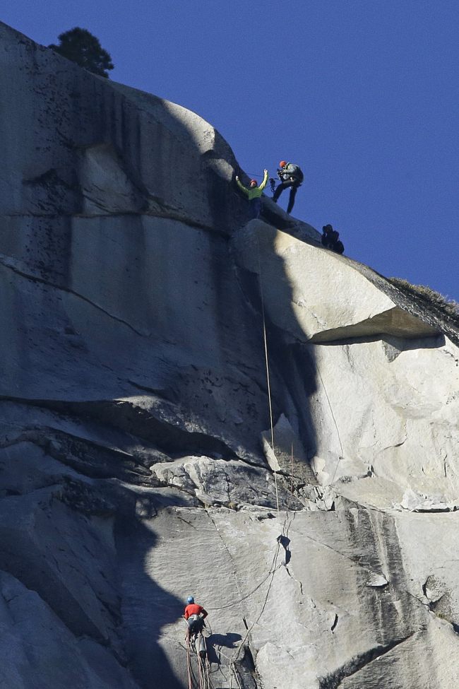 Tommy Caldwell (top) raises his arms after reaching the summit of El Capitan as Kevin Jorgeson (bottom) watches Wednesday, as seen from the valley floor in Yosemite National Park, California.   AP-Yonhap