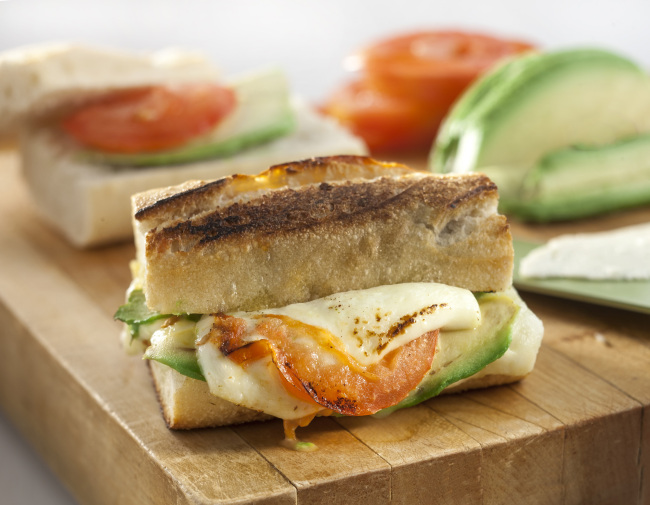 A crusty cheese breakfast sandwich can be adorned with avocado and tomato. (Tribune Content Agency)