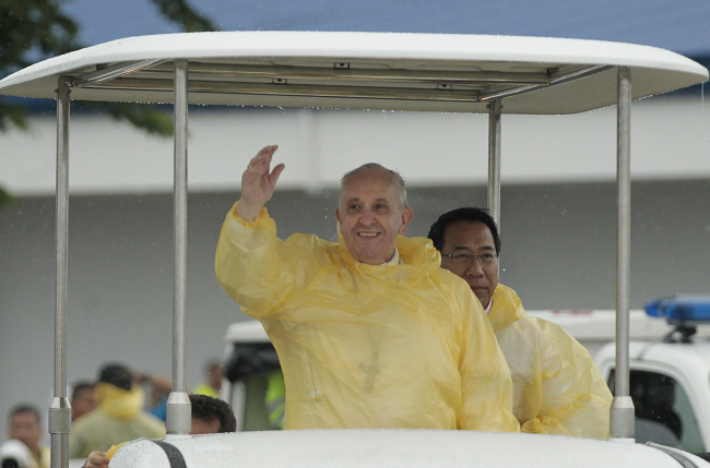 A rain-soaked Pope Francis waves to the faithful on his arrival in Tacloban, Philippines, Saturday.   AP-Yonhap