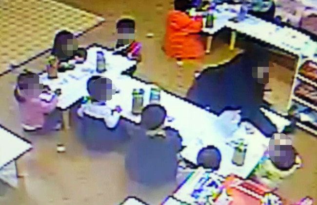 This still image from CCTV footage of a day care center in Bugae-dong, Incheon, shows a 25-year-old female worker punching a preschooler.   Yonhap