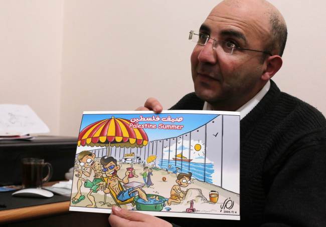 Palestinian cartoonist Ramzy Taweel shows one of his drawing in the West Bank city of Ramallah. (AFP-Yonhap)