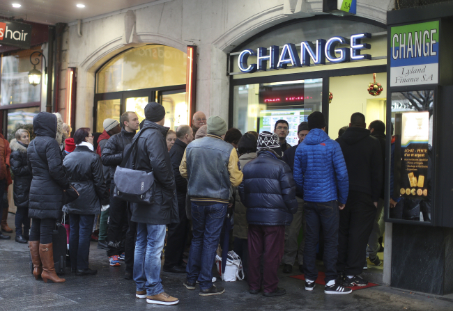 Customers wait in line to exchange their euros for Swiss francs outside a bureau de change currency store in Geneva, Switzerland, Friday.   Bloomberg