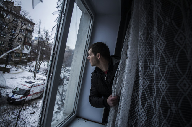 A man looks through a broken window of his flat, hit by Ukrainian Army Artillery, in the Voroshilovsky area of Donetsk, Ukraine, Sunday.   AP-Yonhap