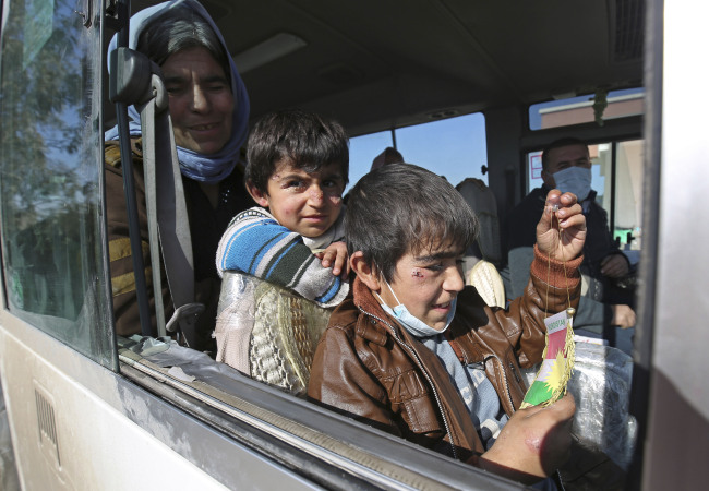 Two Yazidi boys, suffering from several infections from mosquito bites while held by the Islamic State group, wait with their mother inside a bus before being driven to the Kurdish city of Dohuk, in Alton Kupri, outside Kirkuk, Iraq, Sunday.    AP-Yonhap