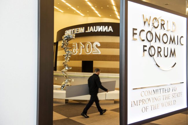 A worker is reflected in a mirror next to a logo of the World Economic Forum at the Congress Center in Davos, Switzerland, Monday. EPA-Yonhap