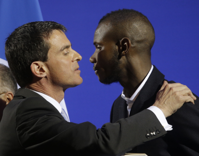 Lassana Bathily (right) kisses French Prime Minister Manuel Valls during a citizenship ceremony in Paris, Tuesday.   AP-Yonhap