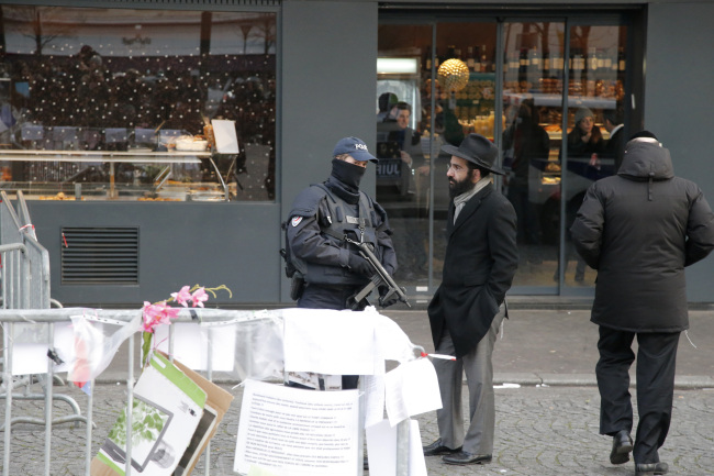 A police officer talks a Jew outside the kosher grocery where Amedy Coulibaly killed four people in a terror attack in Paris on Tuesday.   AP-Yonhap