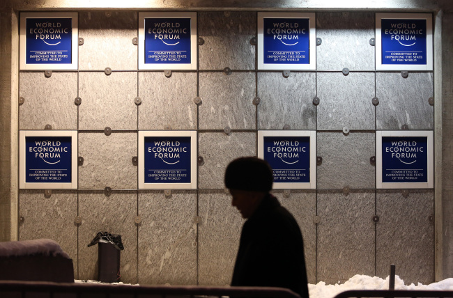 A pedestrian walks past World Economic Forum branding outside the Congress Center in Davos, Switzerland.    Bloomberg