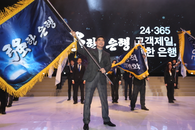 Woori Bank CEO Lee Kwang-goo waves a flag as part of a pledge to become a bank for the people after holding a strategic meeting on Saturday.    Woori Bank