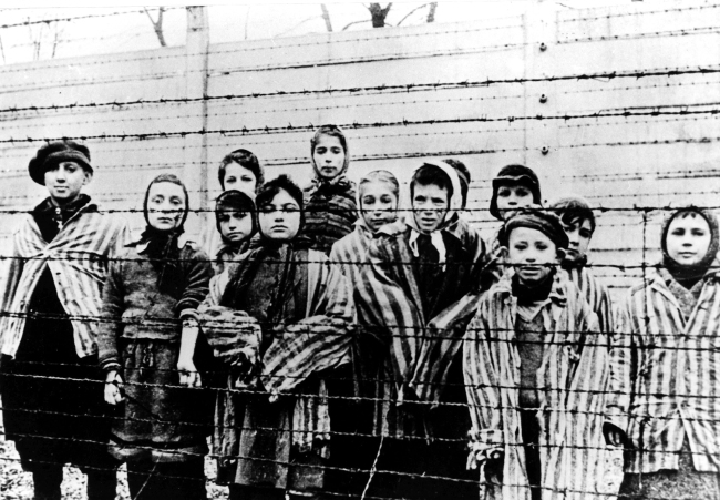 A picture taken just after the liberation by the Soviet army in 1945, shows a group of children wearing concentration camp uniforms behind barbed wire fencing in the Auschwitz Nazi concentration camp.   AFP
