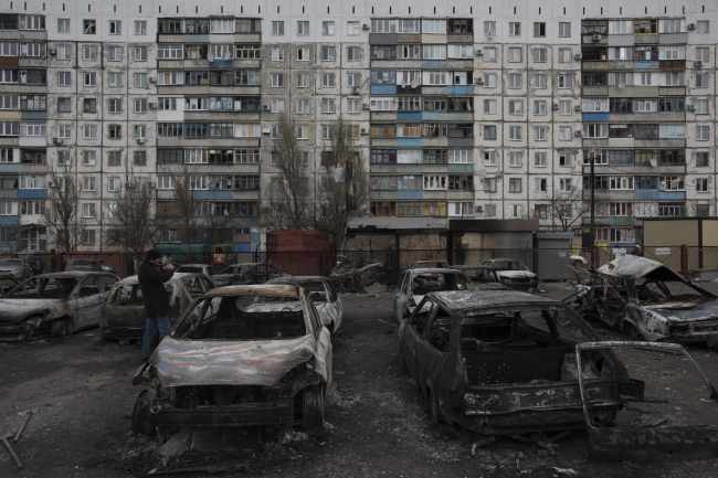 People examine their burned cars, parked outside an apartment building in Vostochniy district of Mariupol, Eastern Ukraine, Sunday. AP-Yonhap