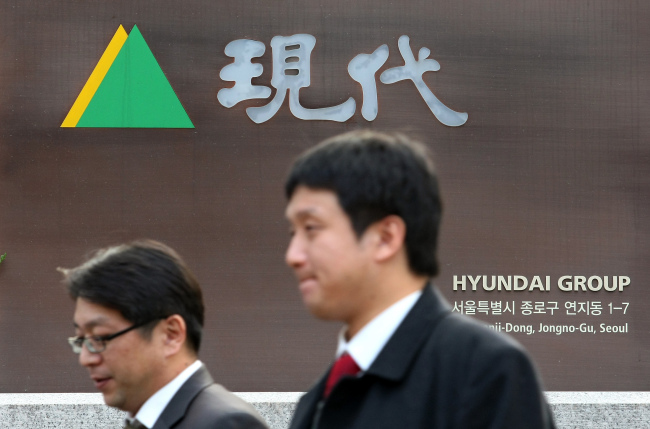 People walk past the logo for Hyundai Group outside the company’s headquarters in Seoul.   Bloomberg