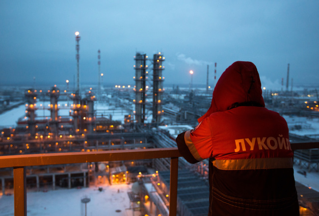 A worker looks out over the illuminated petroleum cracking complex at the Lukoil-Nizhegorodnefteorgsintez oil refinery in Russia.   Bloomberg