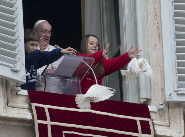 Pope Francis looks at two children as they free doves during the Angelus prayer he celebrated from the window of his studio overlooking St. Peter’s Square, at the Vatican, Monday. AP-Yonhap