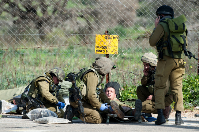 <YONHAP PHOTO-0047> Israeli soldiers treat a wounded soldier near the Israel-Lebanon border, Wednesday, Jan. 28, 2015. A missile fired by the Lebanese Hezbollah group struck an Israeli military convoy on Wednesday, killing two soldiers in an apparent retaliation for a deadly airstrike attributed to Israel that killed many Hezbollah fighters in Syria earlier this month. The violence was the deadliest Hezbollah attack on Israel since a 2006 war between the two sides. (AP Photo/Gili Eliyahu, Jinipix)/2015-01-29 01:40:34/ <저작권자 ⓒ 1980-2015 ㈜연합뉴스. 무단 전재 재배포 금지.>
A wounded Israeli soldier is treated near the Israel-Lebanon border on Wednesday.   AP-Yonhap