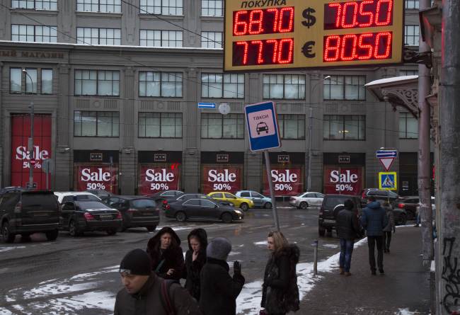 People walk past an exchange office sign showing currency exchange rates in downtown Moscow.   AP-Yonhap