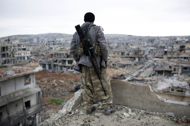 A Syrian Kurdish sniper looks at the rubble in the Syrian town of Kobani on Friday.   AP-Yonhap