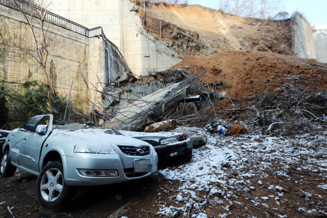Vehicles stand crushed by the collapsed retaining wall in Gwangju on Thursday. (Yonhap)