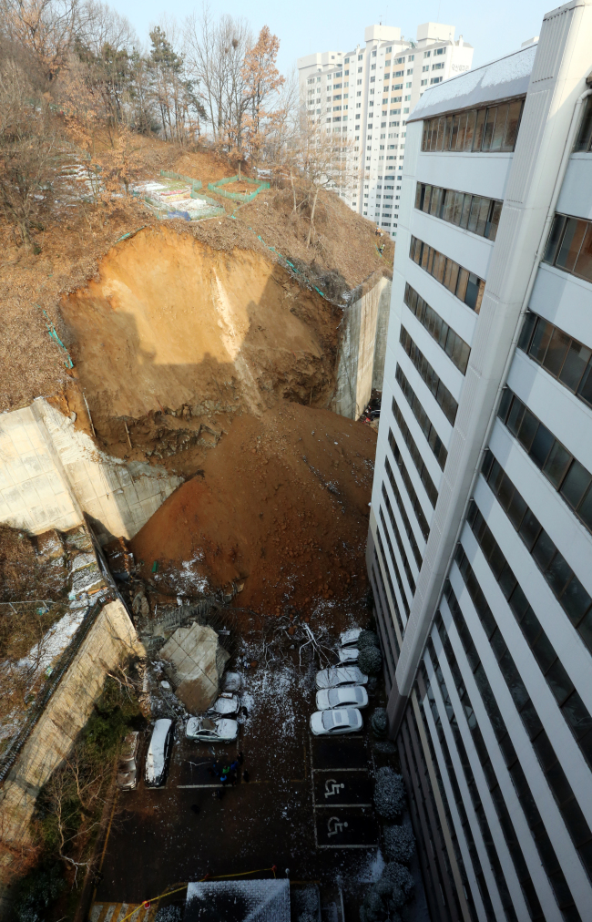 Dozens of vehicles are crushed by the collapsed retaining wall in front of an apartment complex in Gwangju on Thursday.   (Yonhap)