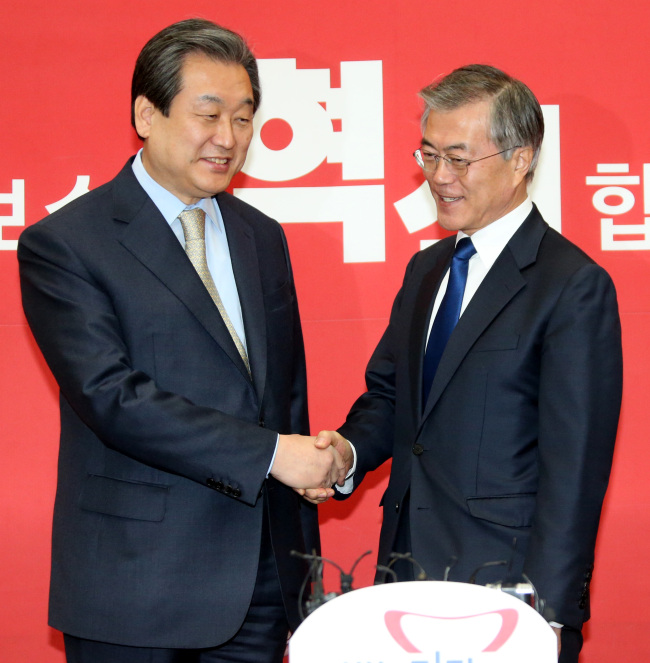 Saenuri Party Chairman Rep. Kim Moo-sung (left) shakes hands with main opposition New Politics Alliance for Democracy Chairman Rep. Moon Jae-in on Monday. Moon was elected to the post on Sunday.    Yonhap