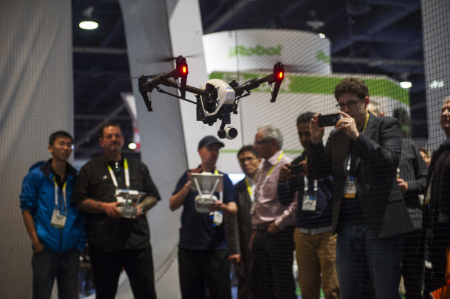 A DJI Inspire 1 drone, manufactured by SZ DJI Technology, is flown during the 2015 Consumer Electronics Show in Las Vegas last month. It was the first time that drone-makers set up their own booths at the world’s largest gadget show.   (Bloomberg)