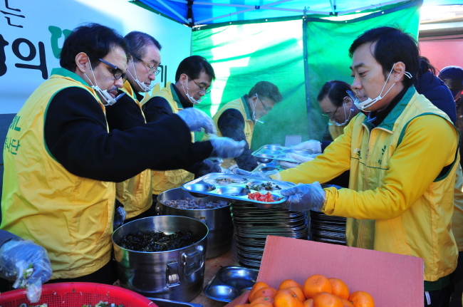 S-Oil CEO Nasser Al-Mahasher (left) serves tteokguk (rice cake soup) along with the company’s table tennis team coach Yoo Nam-Kyu (right) at an annual charity event in front of Yeongdeungpo Gwangya Church on Wednesday. S-Oil employees have provided tteokguk and gift packages to the underprivileged ahead of the Lunar New Year for nine years.   S-Oil