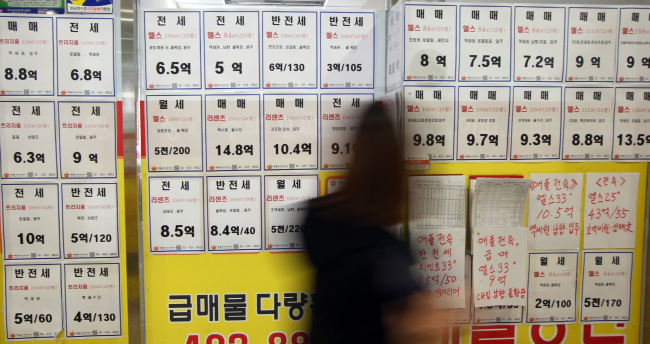 <YONHAP PHOTO-1003> '전세금 너무 비싸네'…서울은 도시근로자 가구 6년치 소득 (서울=연합뉴스) 서명곤 기자 = 서울 시내 아파트의 평균 전세금이 도시 근로자 가구의 6년치 소득과 맞먹는 것으로 나타났다. 부동산114는 작년 12월 말 현재 전국 아파트의 전세 시세와 통계청의 지난해 도시근로자 가구(2인 이상 기준) 소득을 비교한 결과, 서울지역 평균 전세가격이 3억3천849만원으로 도시근로자 가구의 연간 소득(5천682만원)의 5.96배에 달했다고 밝혔다. 사진은 15일 서울 송파구 한 부동산 중개업소 모습. 2015.2.15 seephoto@yna.co.kr/2015-02-15 15:13:45/ <저작권자 ⓒ 1980-2015 ㈜연합뉴스. 무단 전재 재배포 금지.>
A woman walks past a real estate agency in Jamsil, Seoul.   Yonhap