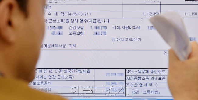 연말정산 결과, 예상보다 환급액은 줄어들고 추가 납부액이 늘어나면서 직장인들의 불만이 포털사이트 등에 폭주하고 있다. 작년엔 환급을 받았지만 올해는 추가납부해야 하는 한 직장인이 2월 월급명세서를 심각하게 바라보고 있다.	 이상섭 기자/babtong@heraldcorp.com
