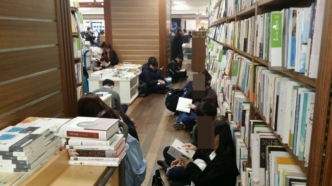 서울 광화문 교보문고에서 사람들이 바닥에 앉아 책을 읽고 있다. 서점 직원은 “주말에는 앉아서 책보는 사람들이 통로를 가득채운다”고 설명했다.