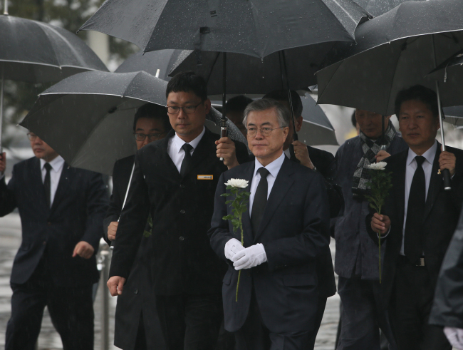 Moon Jae-in (center) pays his respects at the grave of former President Roh Moo-hyun in Gimhae, South Gyeongsang Province, Wednesday. Yonhap