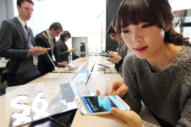 A consumer looks at Samsung Electronics’ new S6 and S6 Edge smartphones displayed at KT’s Olleh Square in Gwanghwamun, Seoul, Monday.   KT
