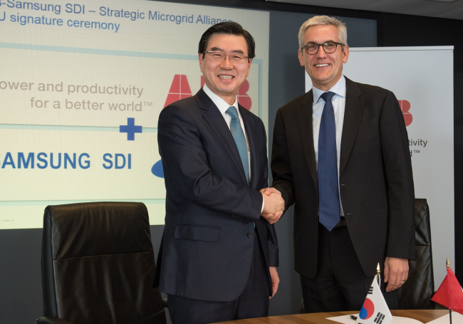 Samsung SDI chief executive Cho Nam-sung (left) holds hands with Ulrich Spiesshofer, chief executive of ABB, after signing a memorandum of understanding for development of energy storage systems in Switzerland on Wednesday.
Samsung SDI