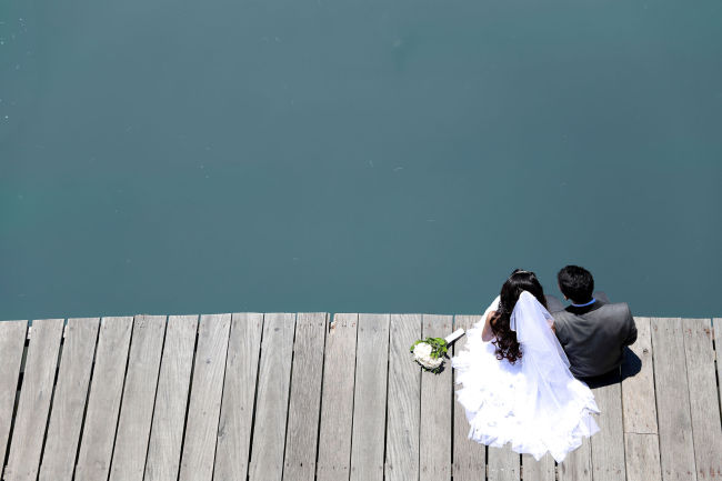A bride and groom sit and watch the river.    123rf
