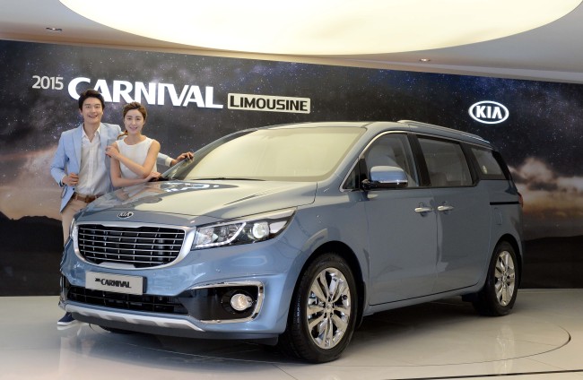 Models pose next to Kia Motors’ 2015 Carnival minivan at a launch ceremony in Seoul on Monday. The new Carnival adds the seven-seat limousine version to the existing nine- and 11-seat family vans.   Kia Motors