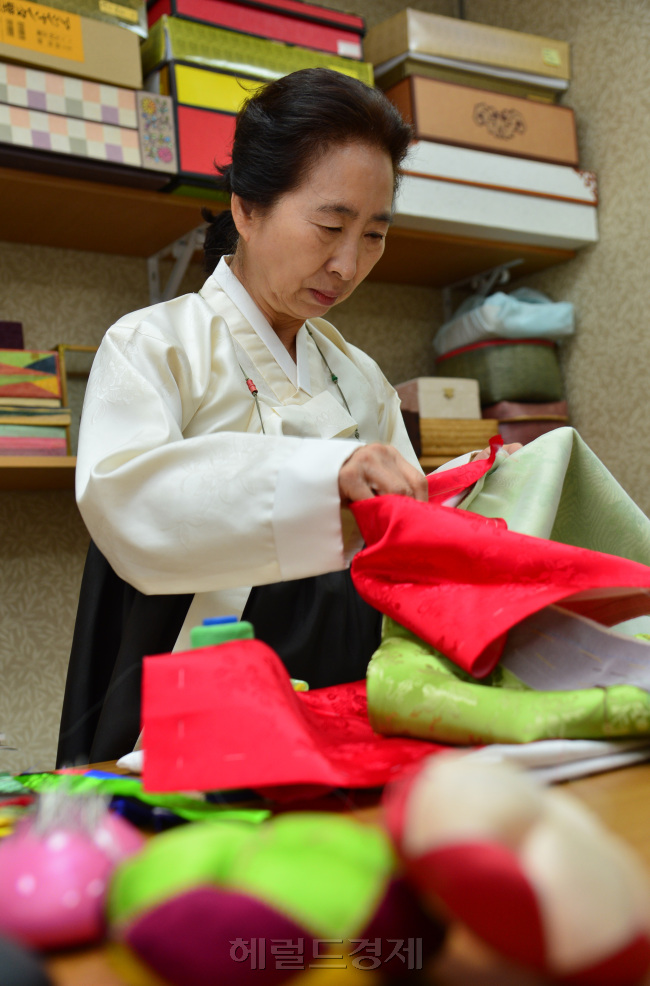 그의 반짓고리에는 고운 색색의 실이 둥그렇게 감겨 바늘에 꿰어지길 기다리고 있다. 그는 그 중 녹색 실을 골라 바늘에 꿰었다. 작은 바늘 구멍을 찾느라 눈을 조리개 맞추듯 할 필요없이 바늘 꿰어주는 도구를 사용했다. 그리고 왼손에 짓다 만 고운 색동저고리를 들고 솔기를 붙여나가기 시작했다. 눈을 감고도 할 수 있는 침선의 세월이지만 그는 묵묵히 조심스럽게 바느질을 이어갔다. 사진=윤병찬기자/yoon4698@heraldcorp.com