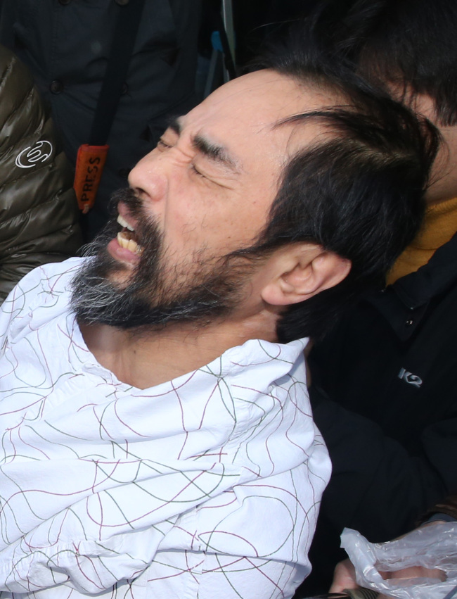 <YONHAP PHOTO-0957> 김기종 검찰 신병인계 (서울=연합뉴스) 임헌정 기자 = 마크 리퍼트 주한 미국대사를 흉기로 습격한 김기종 씨가 14일 오전 서울 송파구 가락동 경찰병원에서 퇴원, 경찰 호송차량에 올라 검찰로 향하던 중 고통스러워하고 있다. 2015.3.14 kane@yna.co.kr/2015-03-14 12:12:15/ <저작권자 ⓒ 1980-2015 ㈜연합뉴스. 무단 전재 재배포 금지.>
Kim Ki-jong.   Yonhap
Kim Ki-jong.   Yonhap