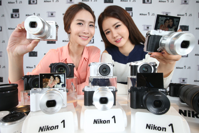 Models pose with Japanese camera-maker Nikon’s new interchangeable-lens digital camera, Nikon 1 J5, at an unveiling event of the product in Seoul on Thursday. The digital camera is capable of shooting 20 continuous frames per second and features a 20.8 megapixel image sensor that allows 4K video recording.    Yonhap
