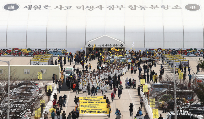 Family members of those killed in last year’s Sewol ferry disaster march from the group memorial alter set up in Ansan, Gyeonggi Province, on Saturday. They plan to march to downtown Seoul in protest of the mandate on investigating the cause and measures related to the disaster.   Yonhap