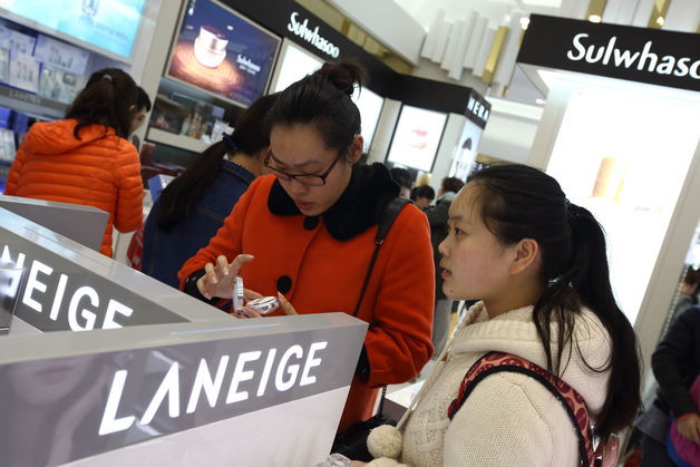 A Chinese tourist (center) samples AmorePacific’s Laneige cosmetics at a Lotte Duty Free store on Jejudo Island. Bloomberg