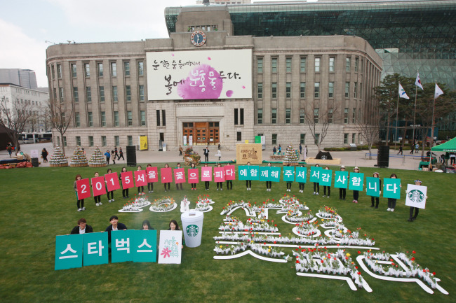 Starbucks officials perform in front of Seoul City Hall as part of a joint environmental campaign on Wednesday.    Yonhap