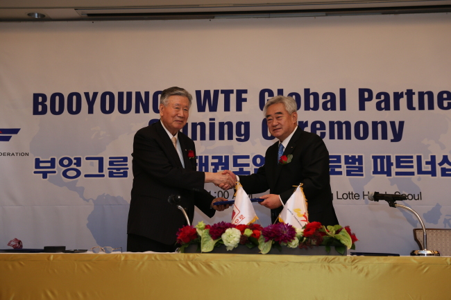 Booyoung Group chairman Lee Joong-keun (left) shakes hands with World Taekwondo Federation president Choue Chung-won in a ceremony to seal a new global partnership deal between the two sides, on Wednesday in Seoul. As a sponsor, Booyoung Group will provide WTF with a total of $10 million (11 billion won) for six years until the 2020 Tokyo Olympics.   Booyoung Group