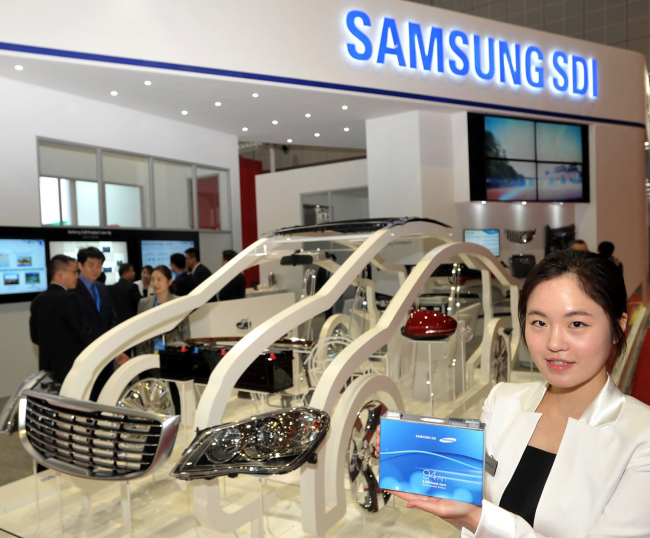 An official from Samsung SDI, a battery manufacturer, poses with a battery for an electric vehicle at the 16th Shanghai International Automobile Industry Exhibition in Shanghai on Monday.   Yonhap