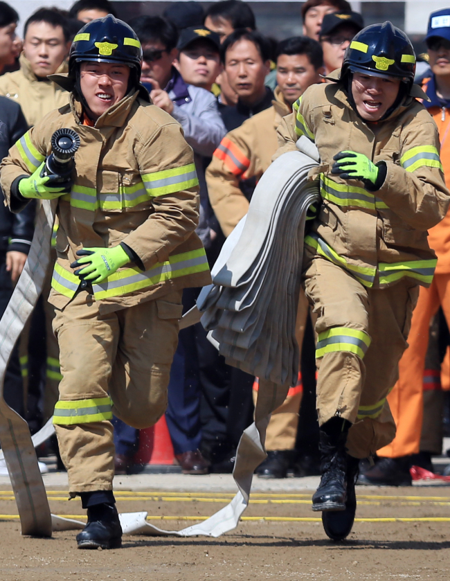 <YONHAP PHOTO-1049> 우리는 한 팀 (서울=연합뉴스) 홍해인 기자 = 서울시 소방재난본부 주최로 21일 오전 서울 방학동 소방학교 구조구급교육센터에서 열린 소방기술 경연대회 '지상 화재진압(속도방수)' 경연에 참가한 소방대원들이 소방 호스를 들고 방수 지점을 향해 달리고 있다. 2015.4.21 hihong@yna.co.kr/2015-04-21 13:03:59/ <저작권자 ⓒ 1980-2015 ㈜연합뉴스. 무단 전재 재배포 금지.>
Firefighters participate in a firefighting skill competition hosted by Seoul Metropolitan Fire and Disaster Headquarters on Monday in Banghak-dong, Seoul.   Yonhap